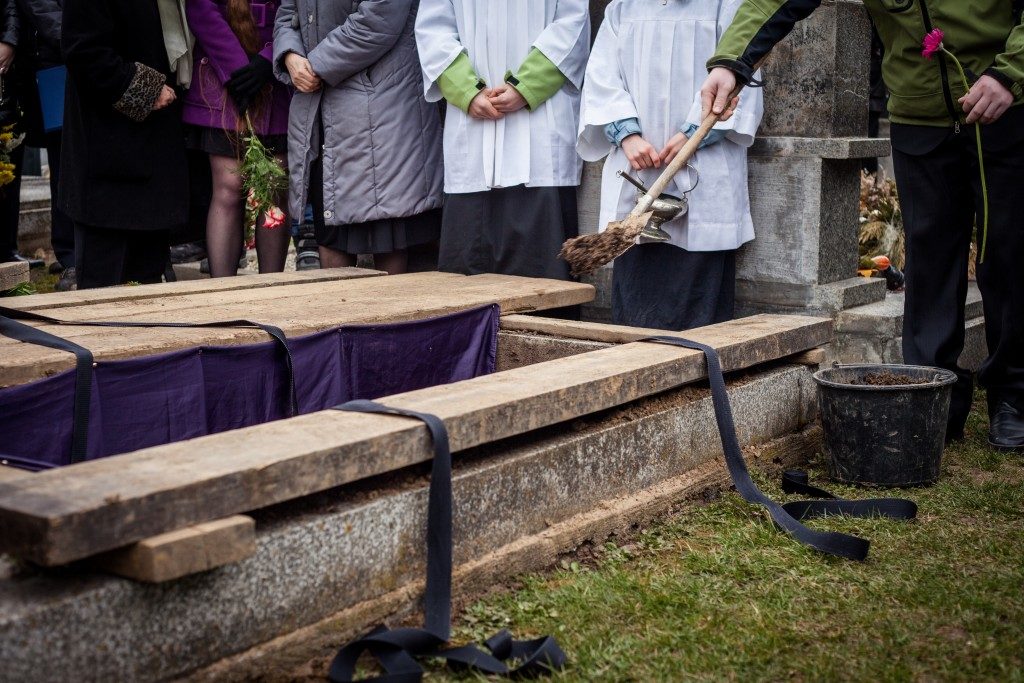 Mourners staying by the opened grave