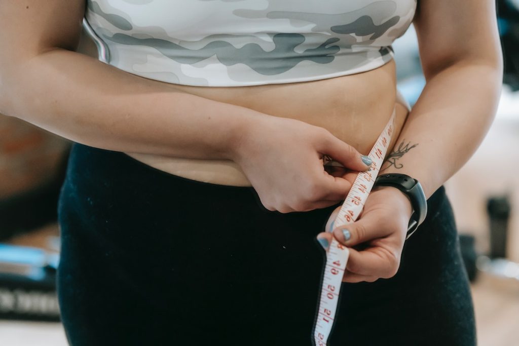 Plump woman in sportswear with measuring tape
