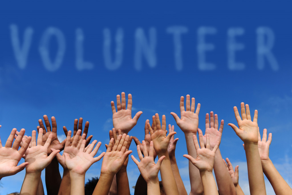 Hands raised to the sky with Volunteer text in clouds